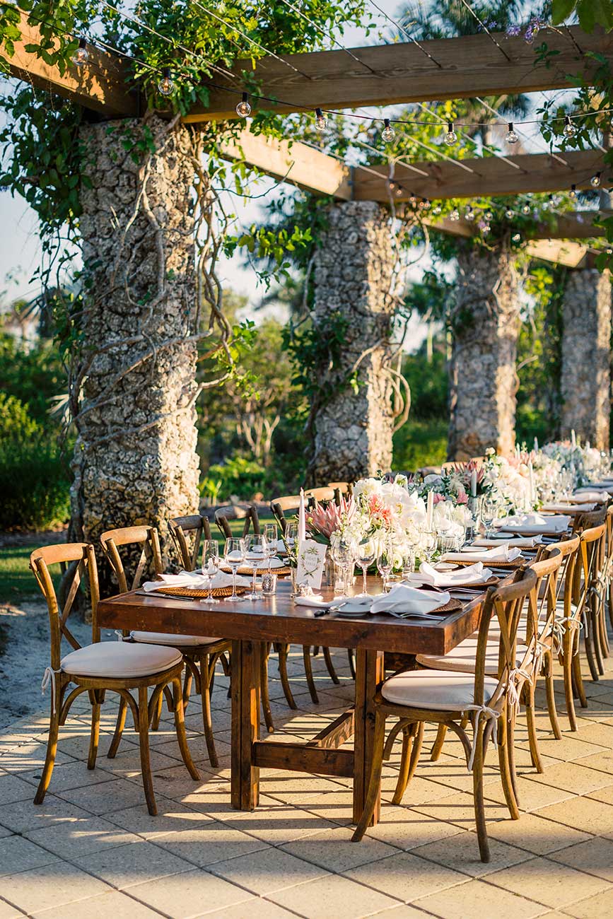 Outdoor wedding reception tablescape with flowers, dinnerware and crystal