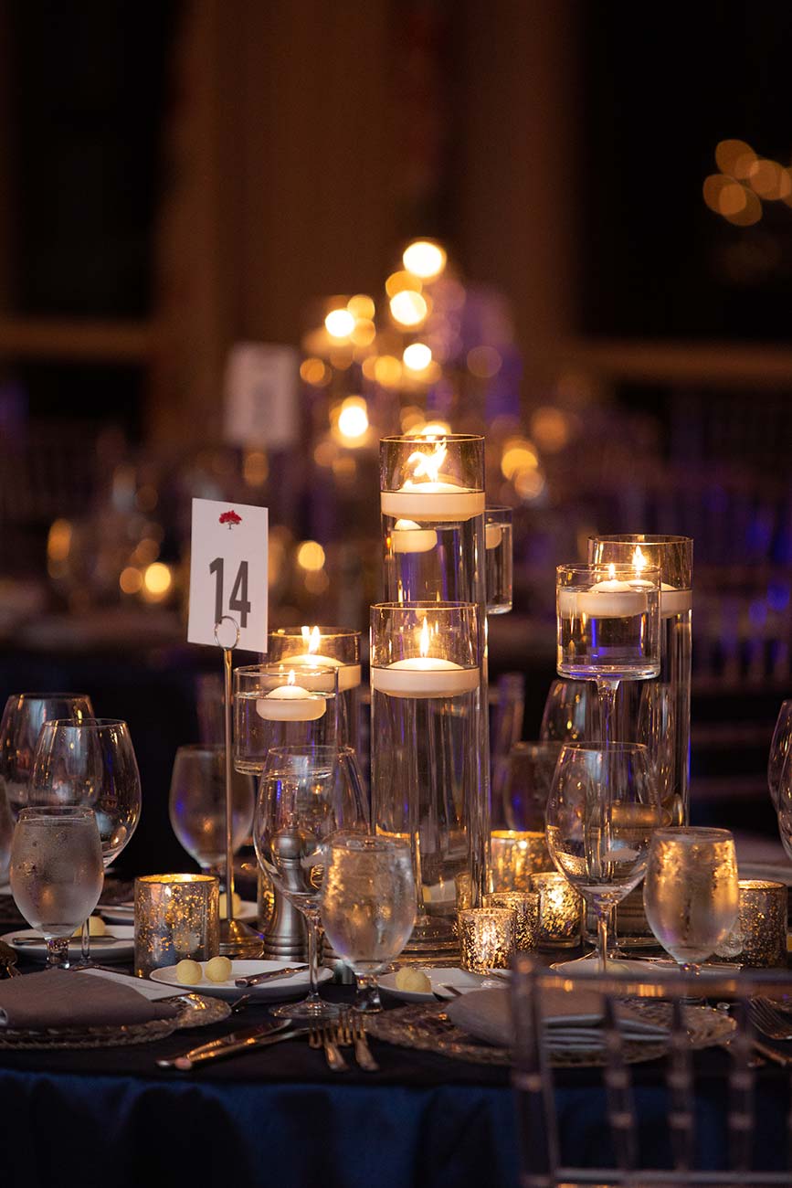 Tabletop view of wedding guest table covered in crystal candle holders and table number